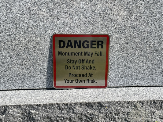 A small warning sign installed on a granite monument