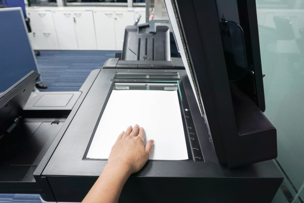 A person placing a sheet of paper on a scanner