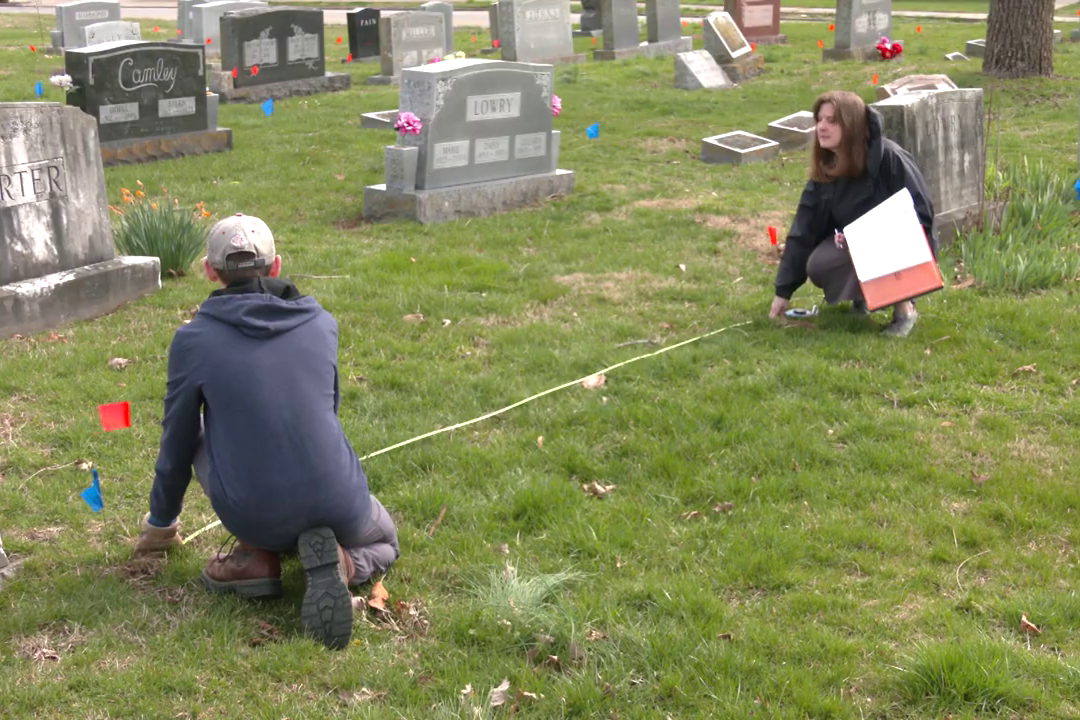 Employees measuring a portion of a cemetery lot